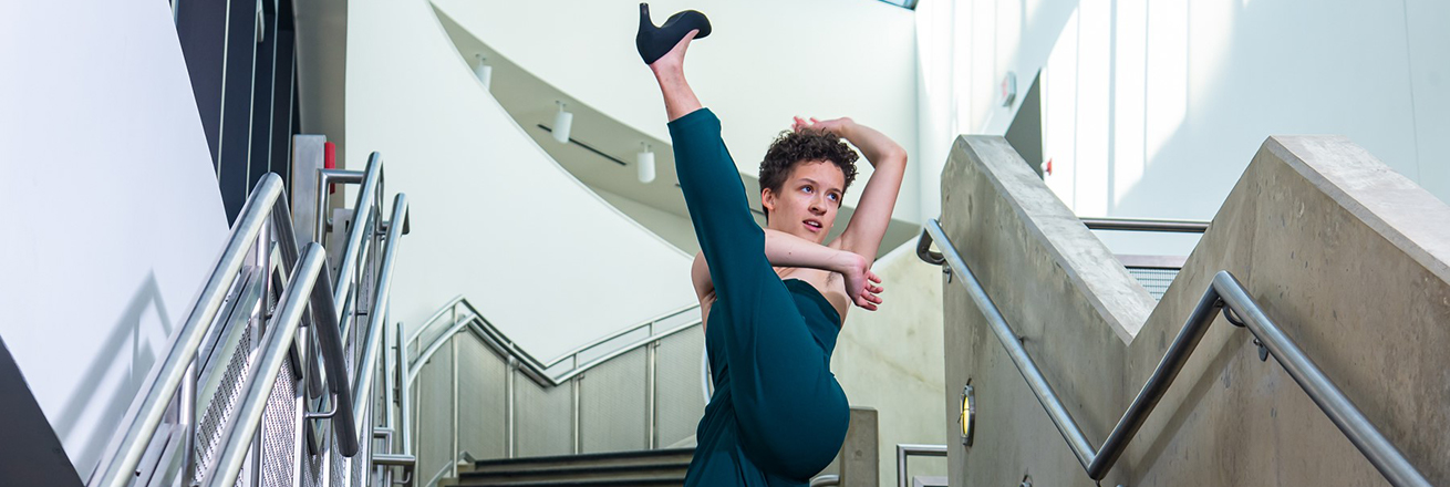 A dancer on a staircase kicks one leg high