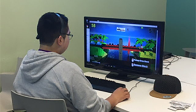 A young person sitting at a computer demonstrating the Scalebridge game.