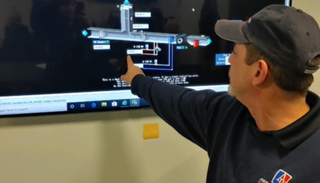 An AU Facilities staff member pointing to a schematic on a screen.