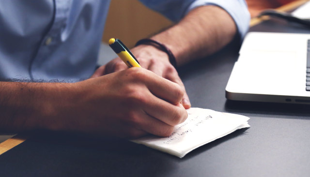man writing on a scrap of paper