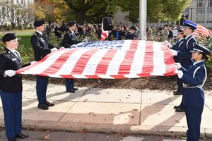 Men and women in military uniform holding the American flag.